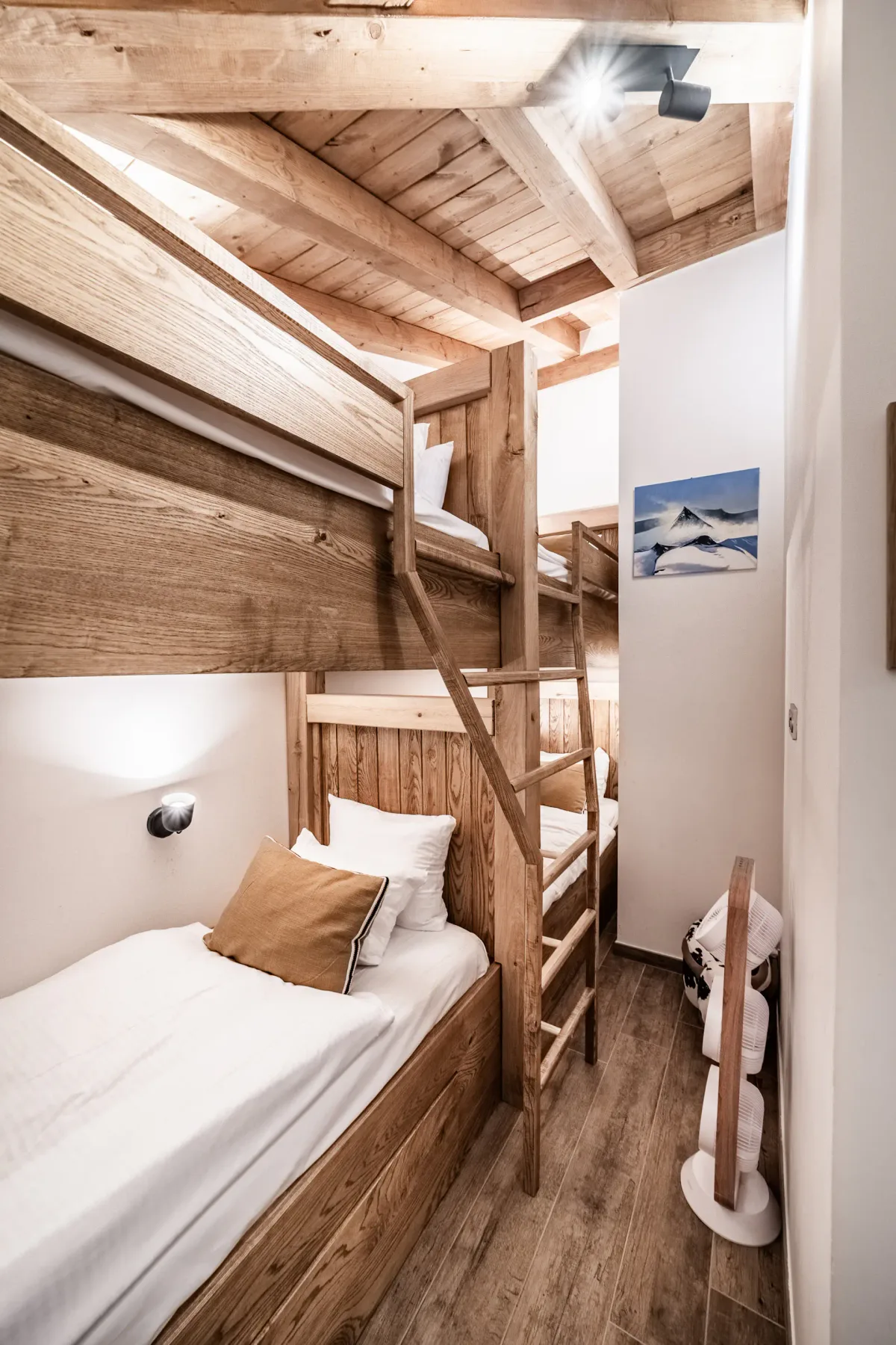 Un dormitorio compacto con literas de madera, ropa de cama blanca y una escalera.