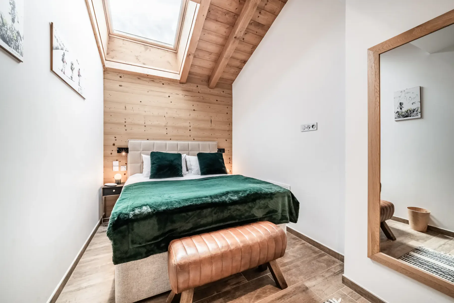 Un dormitorio con una cama cubierta de ropa de cama verde bajo una claraboya.