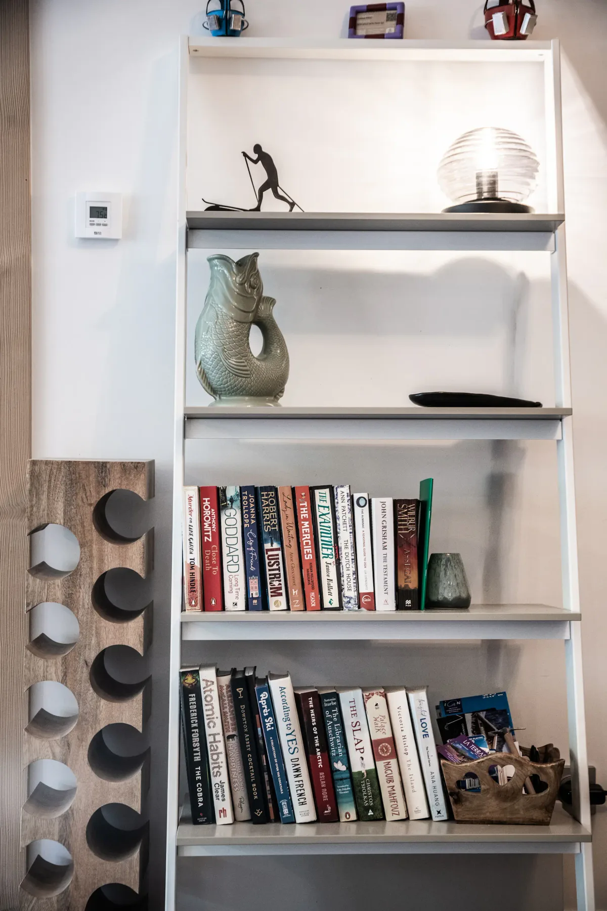 Una estantería alta muestra libros, esculturas y objetos decorativos.