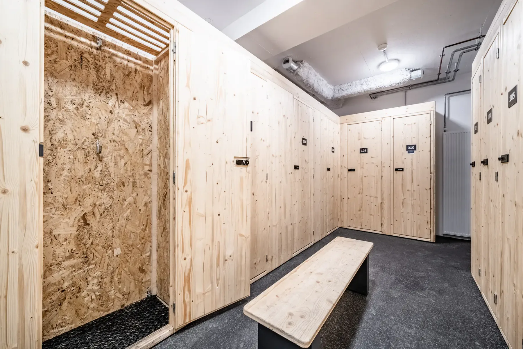 Zona común: Un vestuario con filas de taquillas de madera y un banco central.