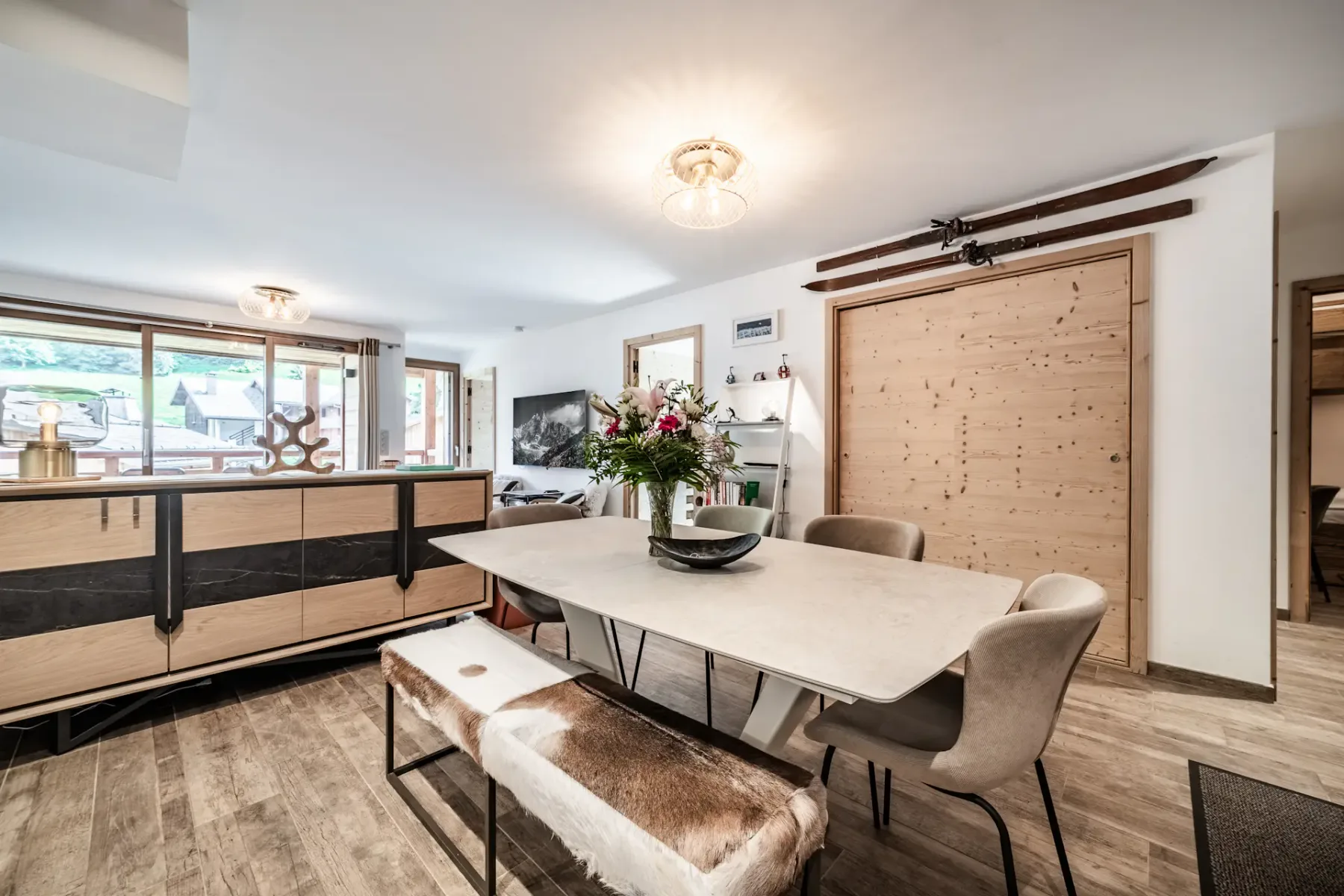 Un comedor con una mesa larga y sillas junto a una ventana grande.