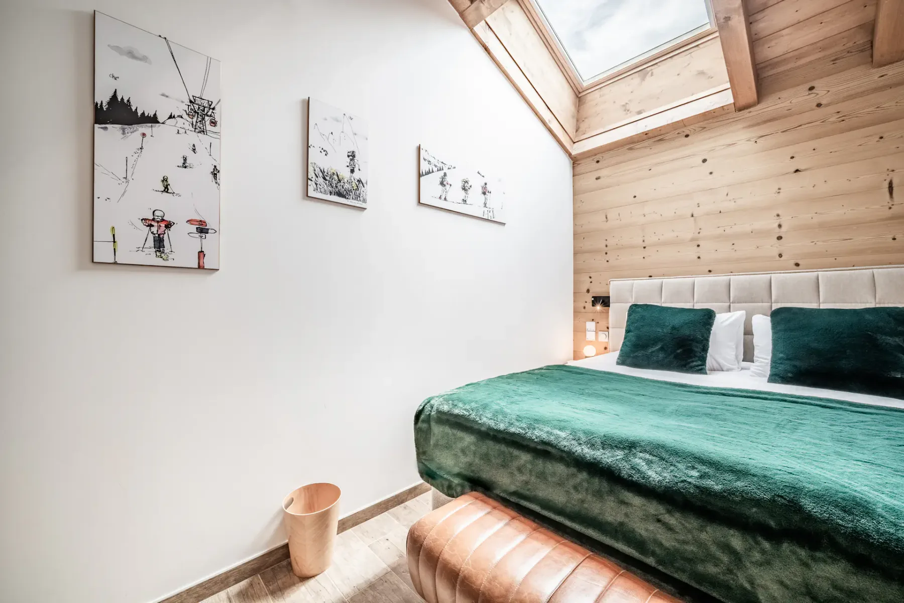 Un dormitorio con una cama verde bajo una claraboya.