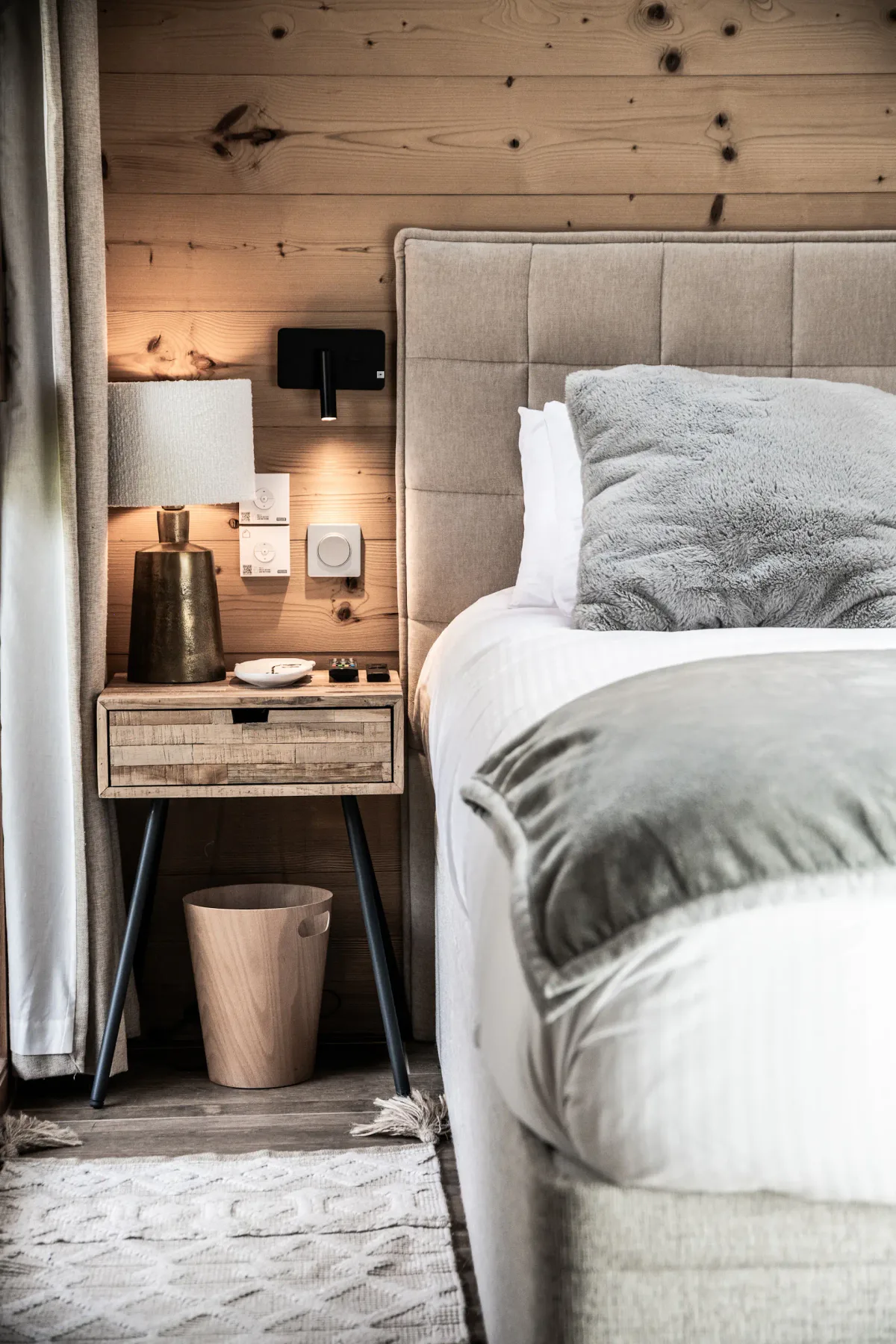 Un dormitorio con una cama junto a una mesita de madera.