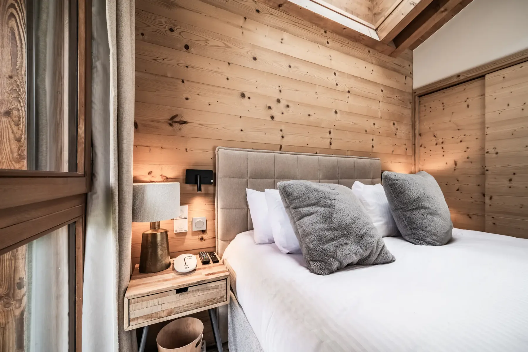 Un dormitorio con una cama bien tendida y paredes revestidas de madera.