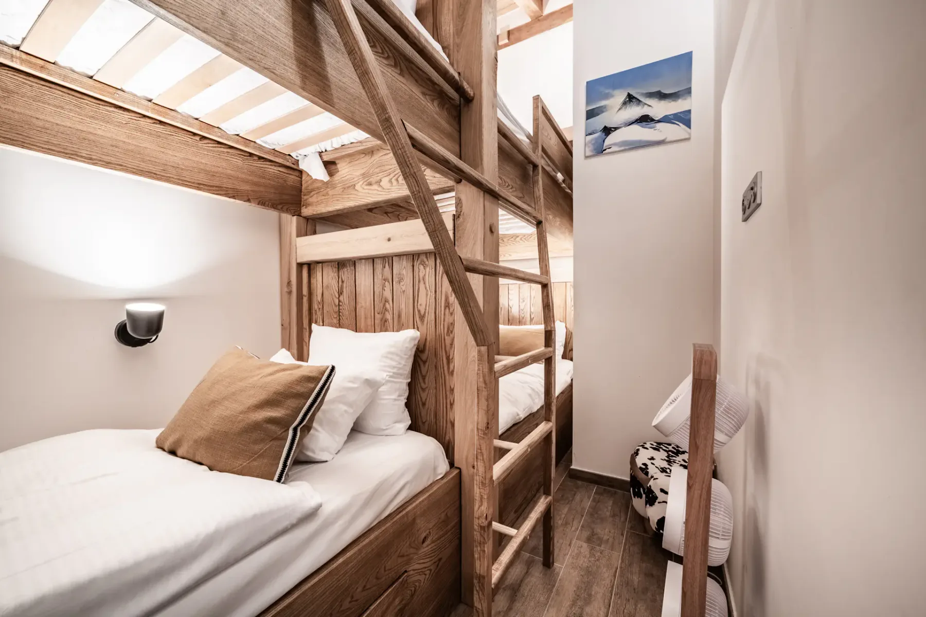 Un dormitorio con una litera de madera y ropa de cama blanca.