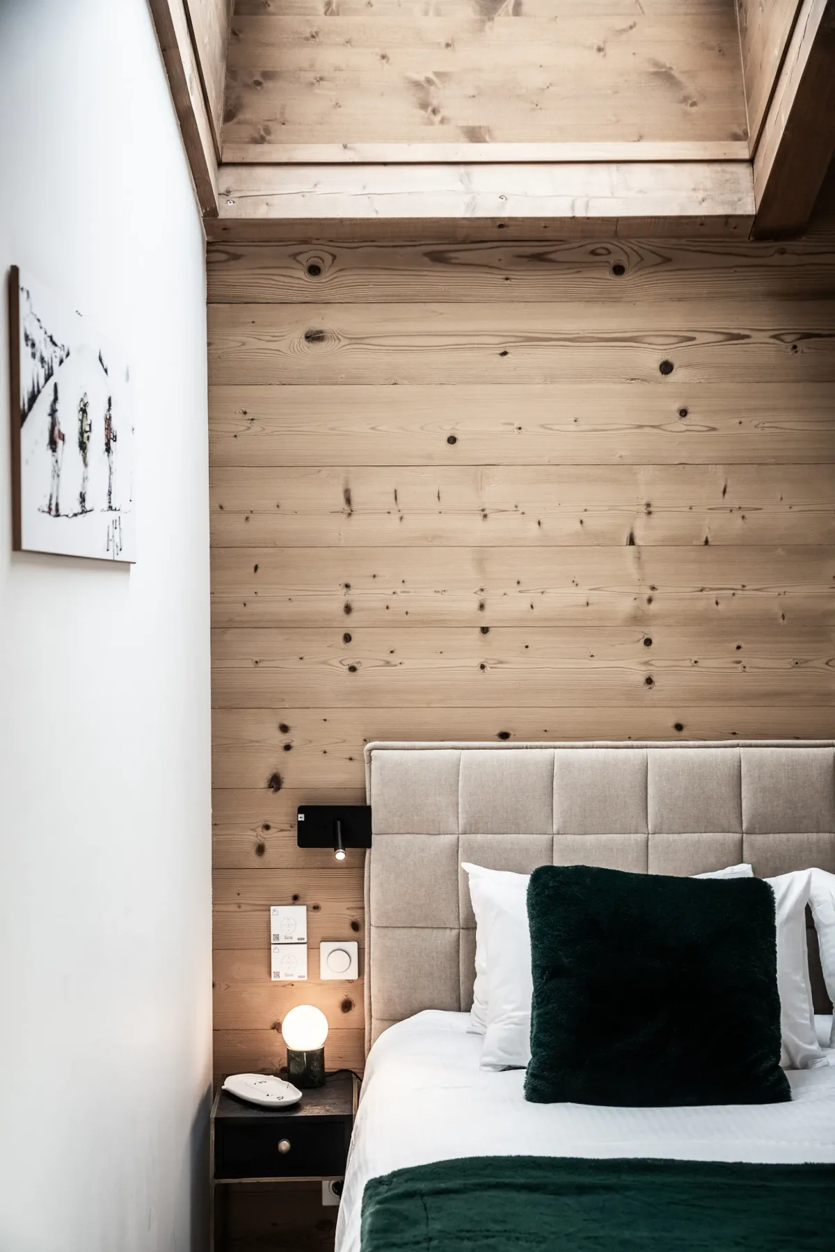 Un dormitorio con una cama junto a una pared revestida de madera clara.