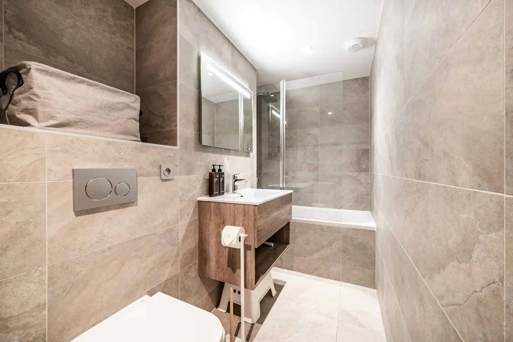 Un baño alicatado con lavabo, espejo y bañera.
