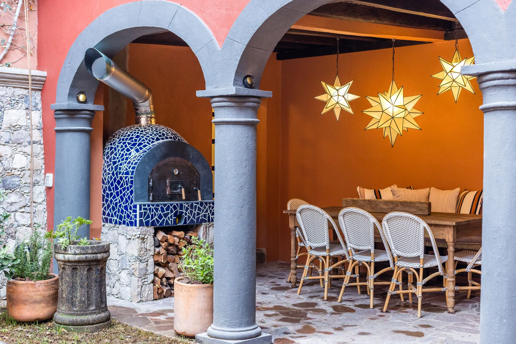 An arched dining area with a long table and a blue-tiled oven.