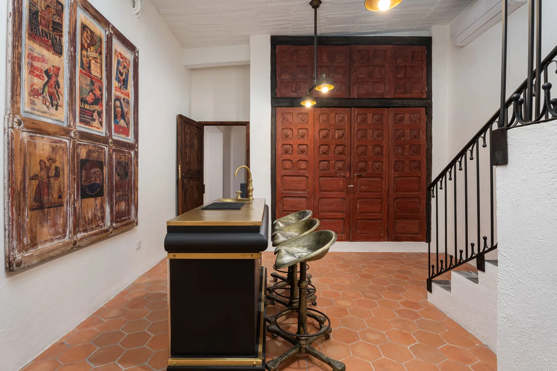 A room with a dark counter, metal seating, and large wooden doors.