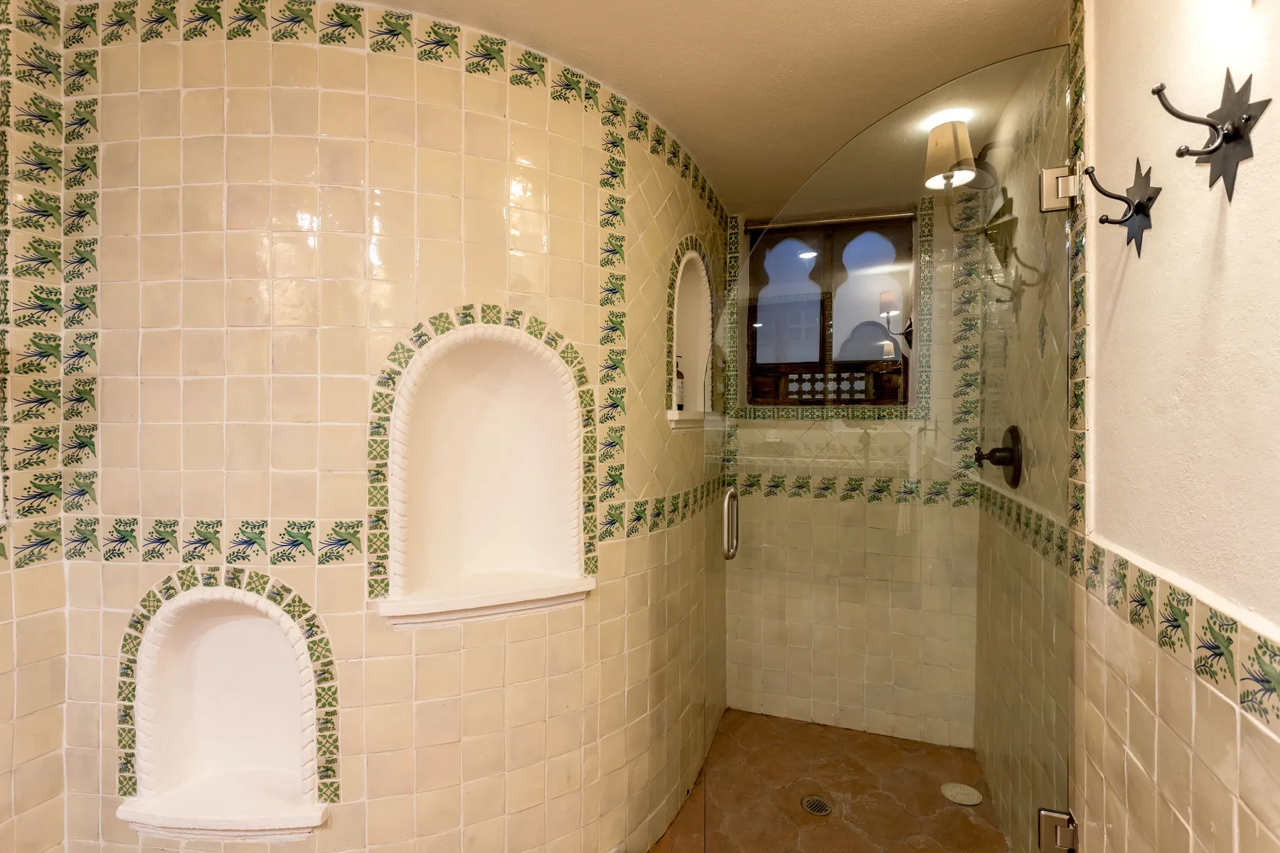 A tiled bathroom with built-in wall niches and a glass shower.