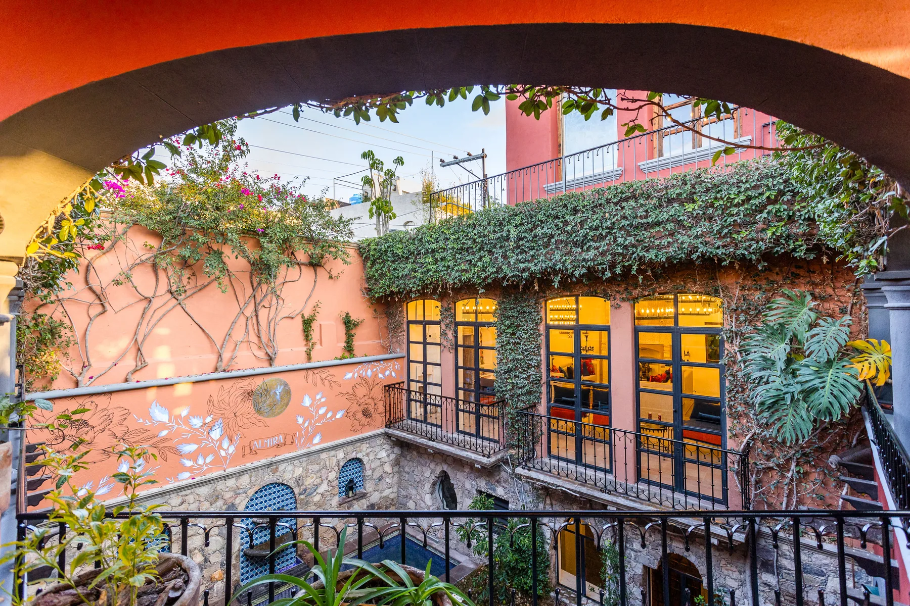 A courtyard viewed through an arch, with ivy-covered walls and illuminated windows.