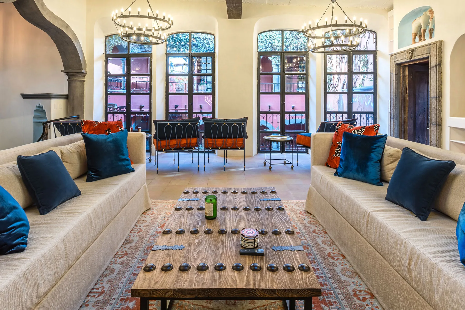 A bright lounge with cushioned seating, arched windows, and a wooden game table.