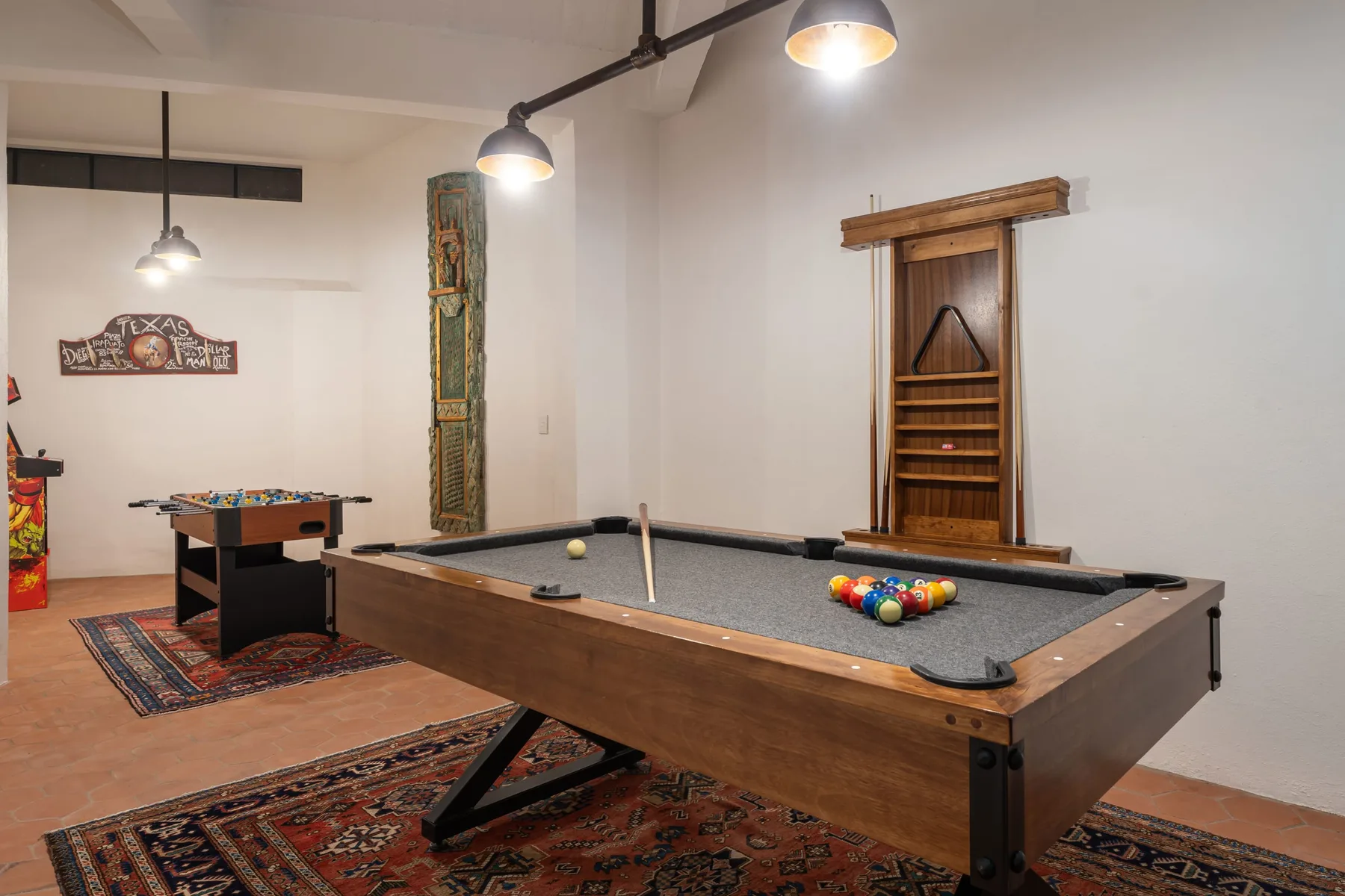 A game room with a pool table, colorful balls, and patterned rugs.