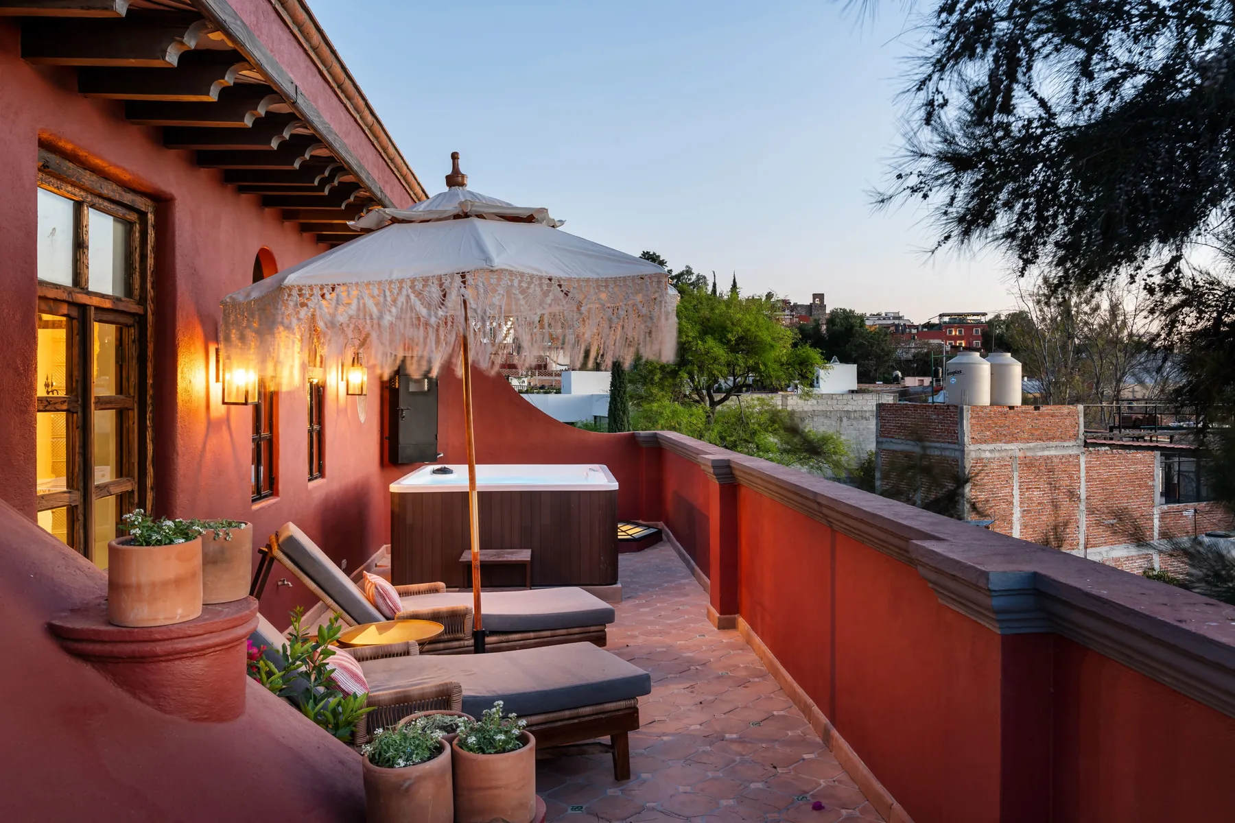 A rooftop terrace with lounge seating, a large umbrella, and a hot tub.