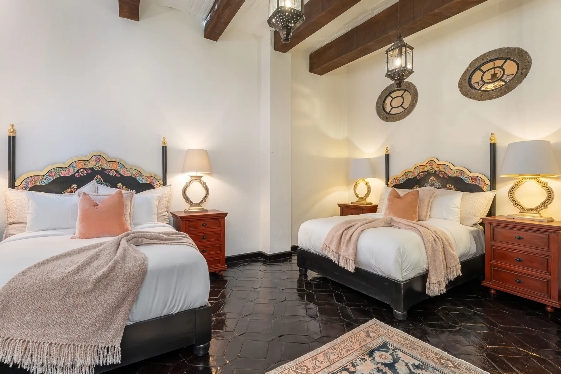 A bedroom with two beds, bedside tables, and exposed wooden ceiling beams.