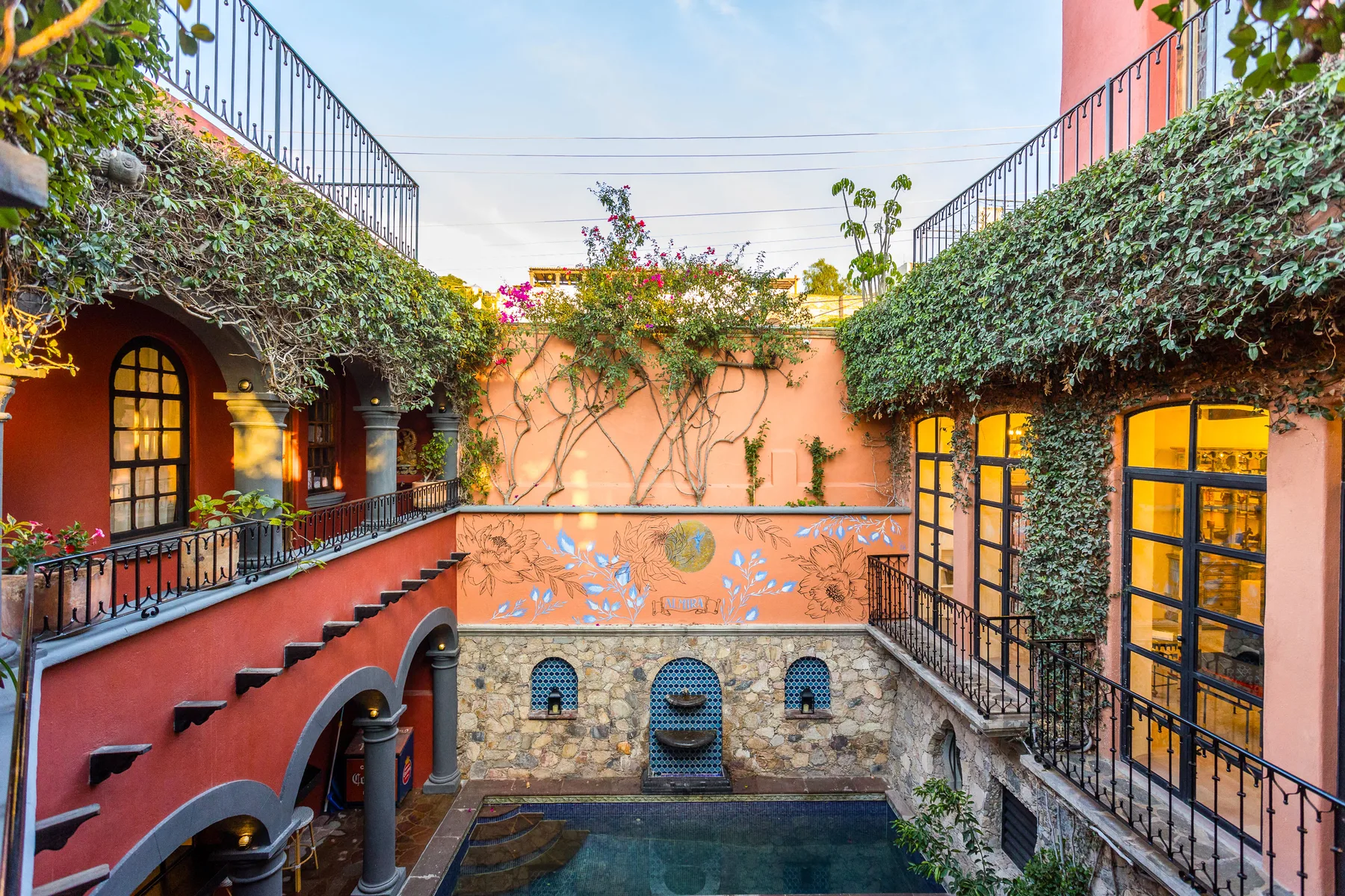 An enclosed courtyard with a small pool, arched windows, and leafy walls.