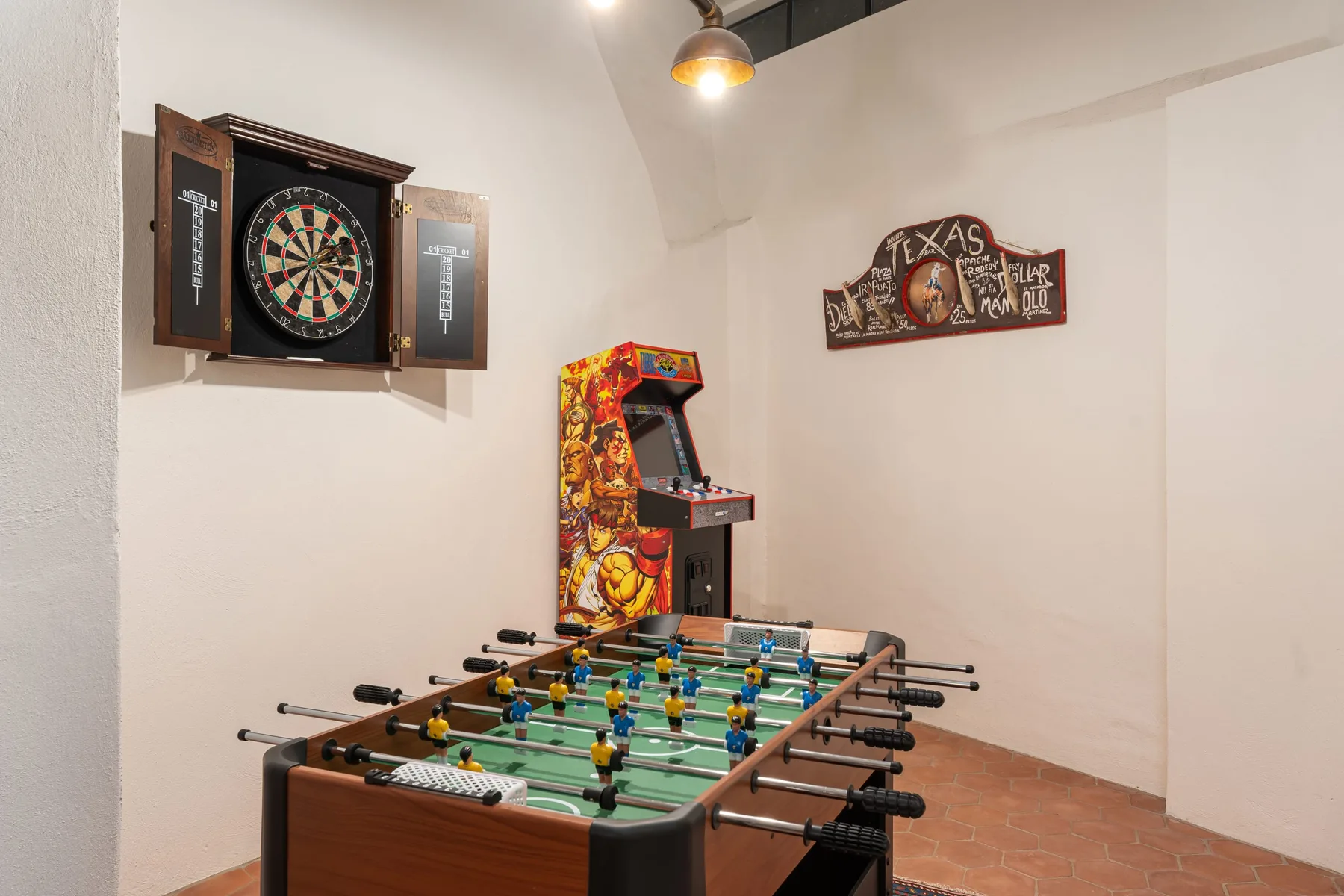 A game room features a foosball table, arcade game, and dartboard.