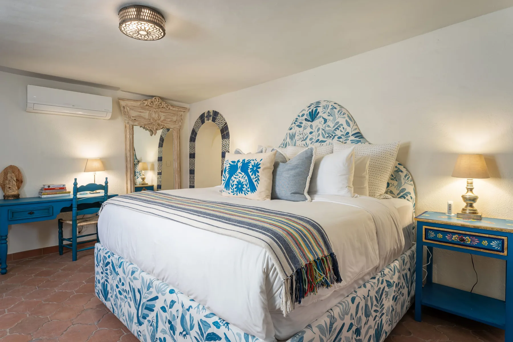 A bedroom with a large bed, patterned bedding, and matching blue bedside tables.