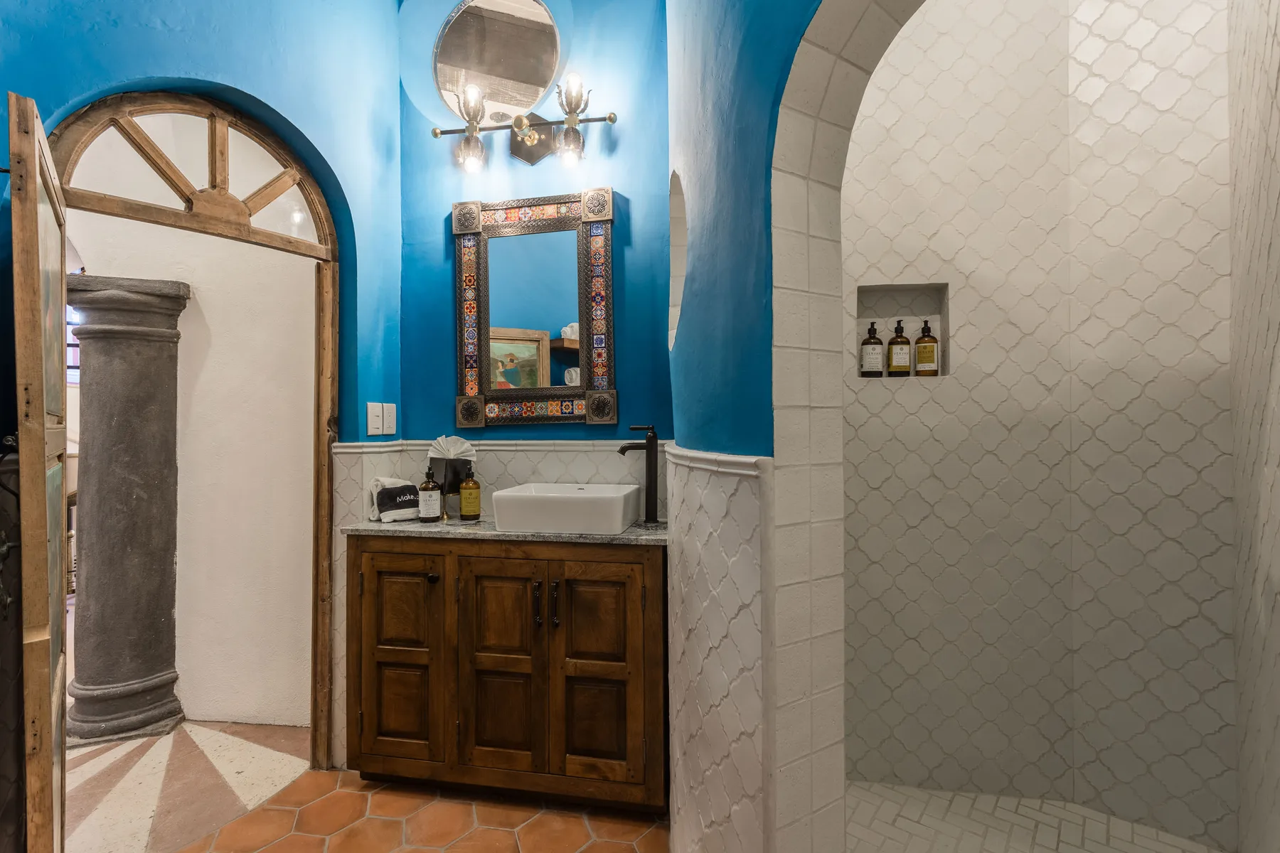 A bathroom with a wooden vanity and a tiled shower area.