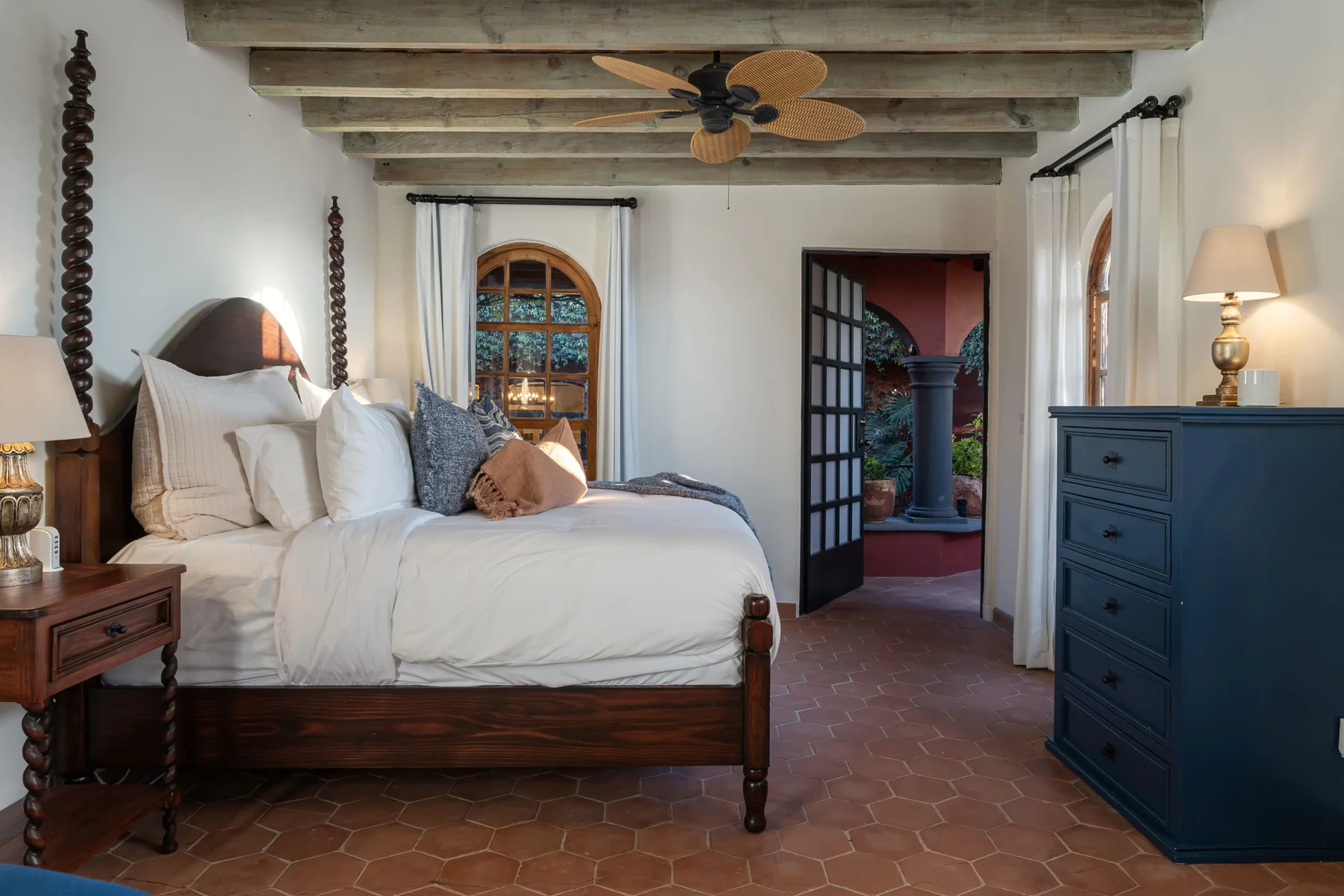 A bedroom with a wooden bed, white bedding, and exposed ceiling beams.