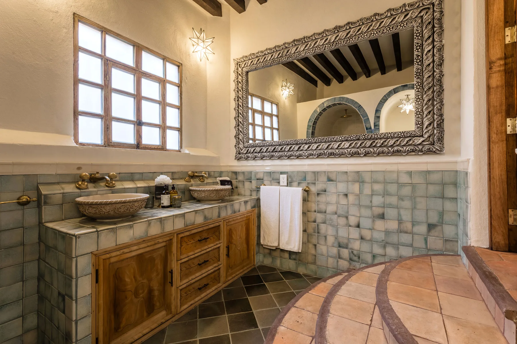 A tiled bathroom vanity with two sinks and a large wall mirror.
