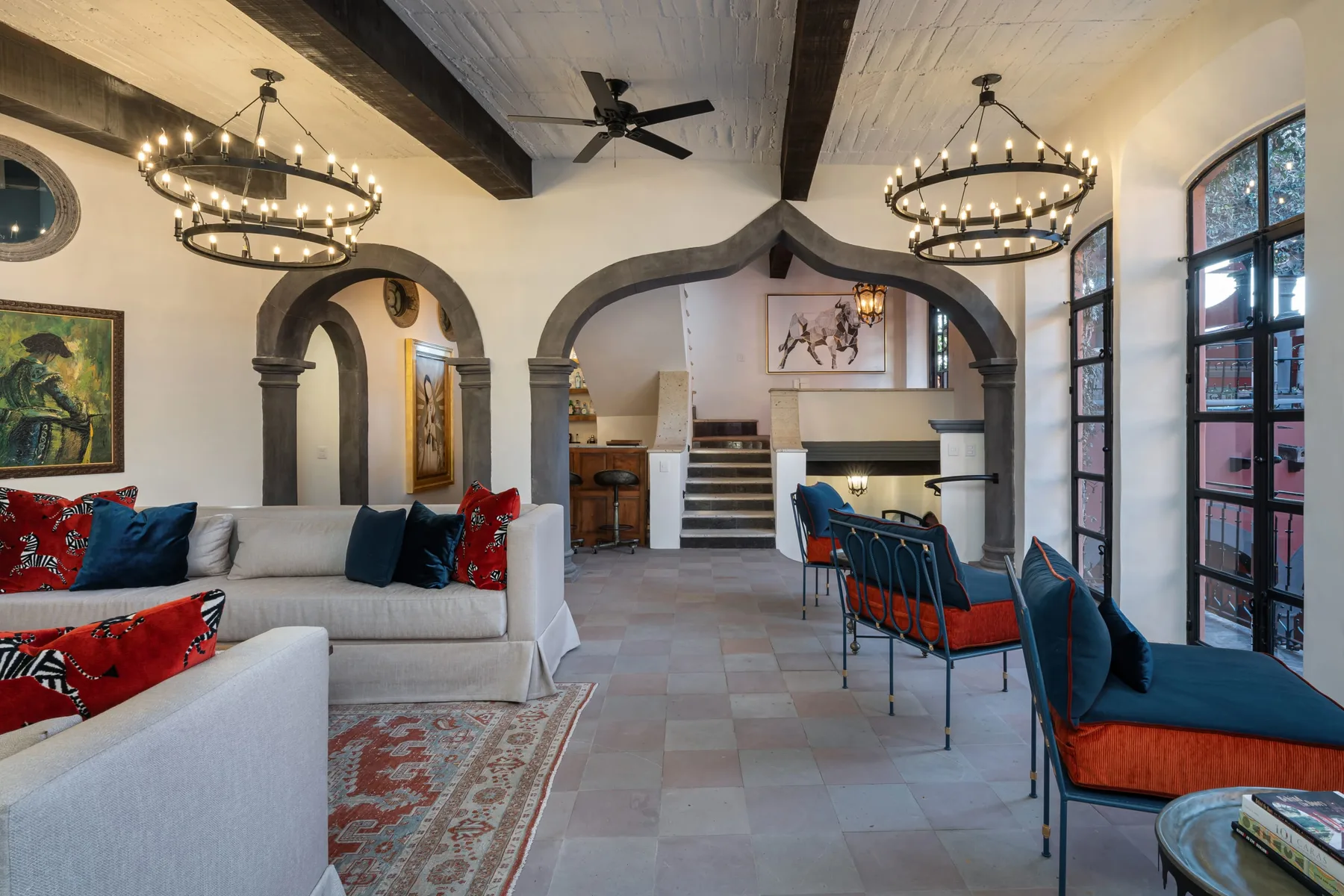 A spacious living and dining room with arched openings and long tables.