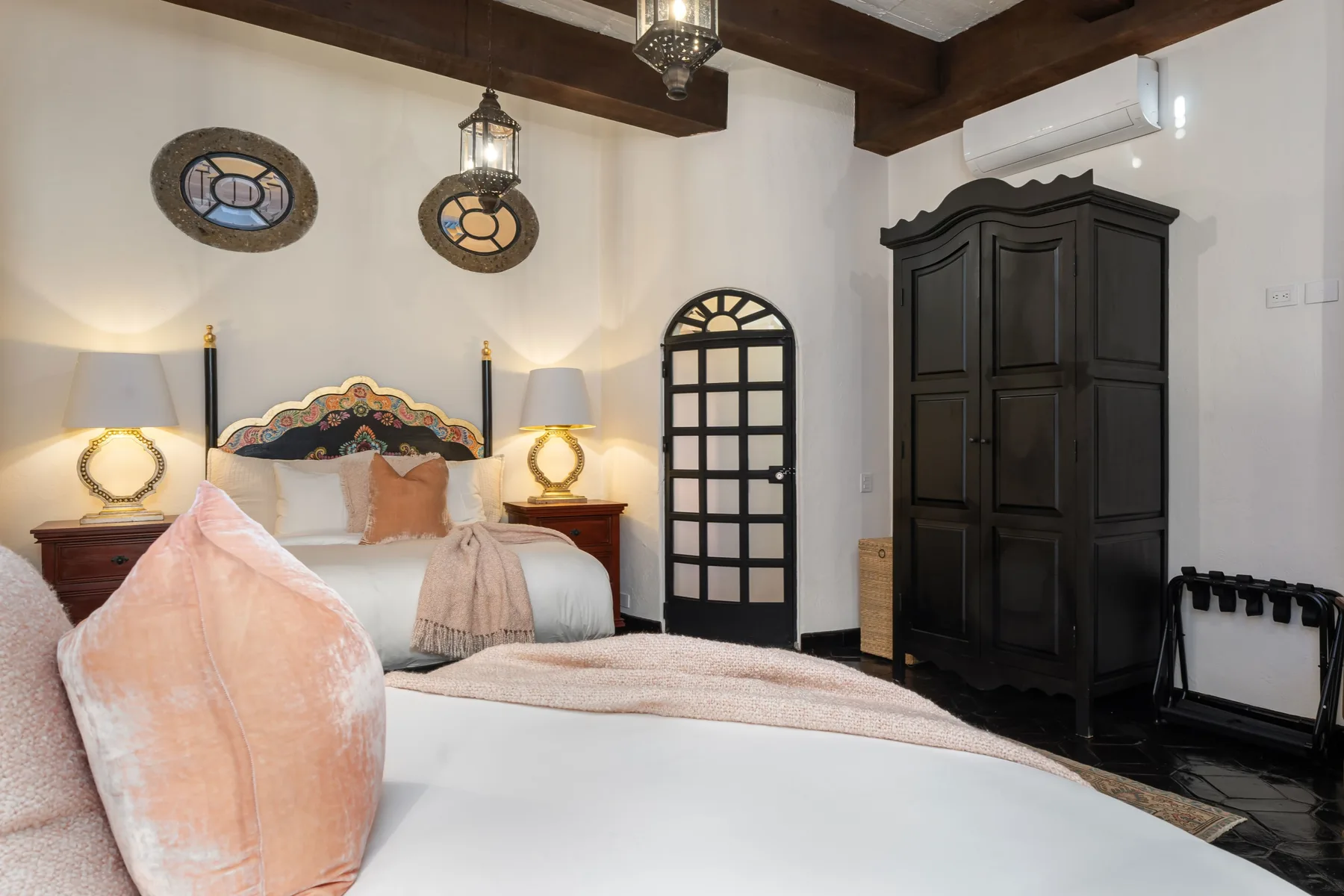 A bedroom with a bed, dark wooden wardrobe, and arched doorway.