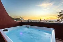 A rooftop hot tub overlooks the city at sunset.