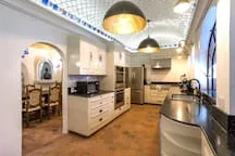 A kitchen with a long counter, cabinets, and dining seating.