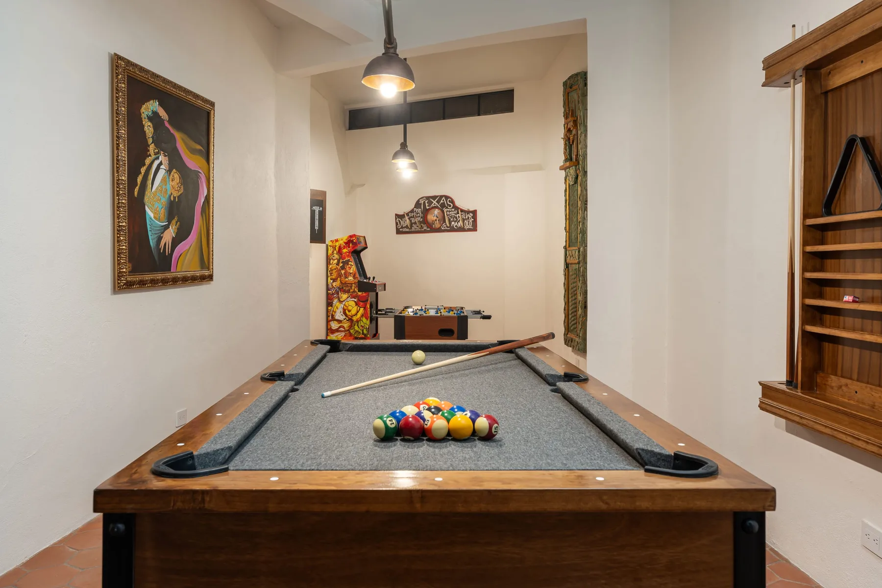 A billiards room with a pool table and colorful balls arranged on the felt.