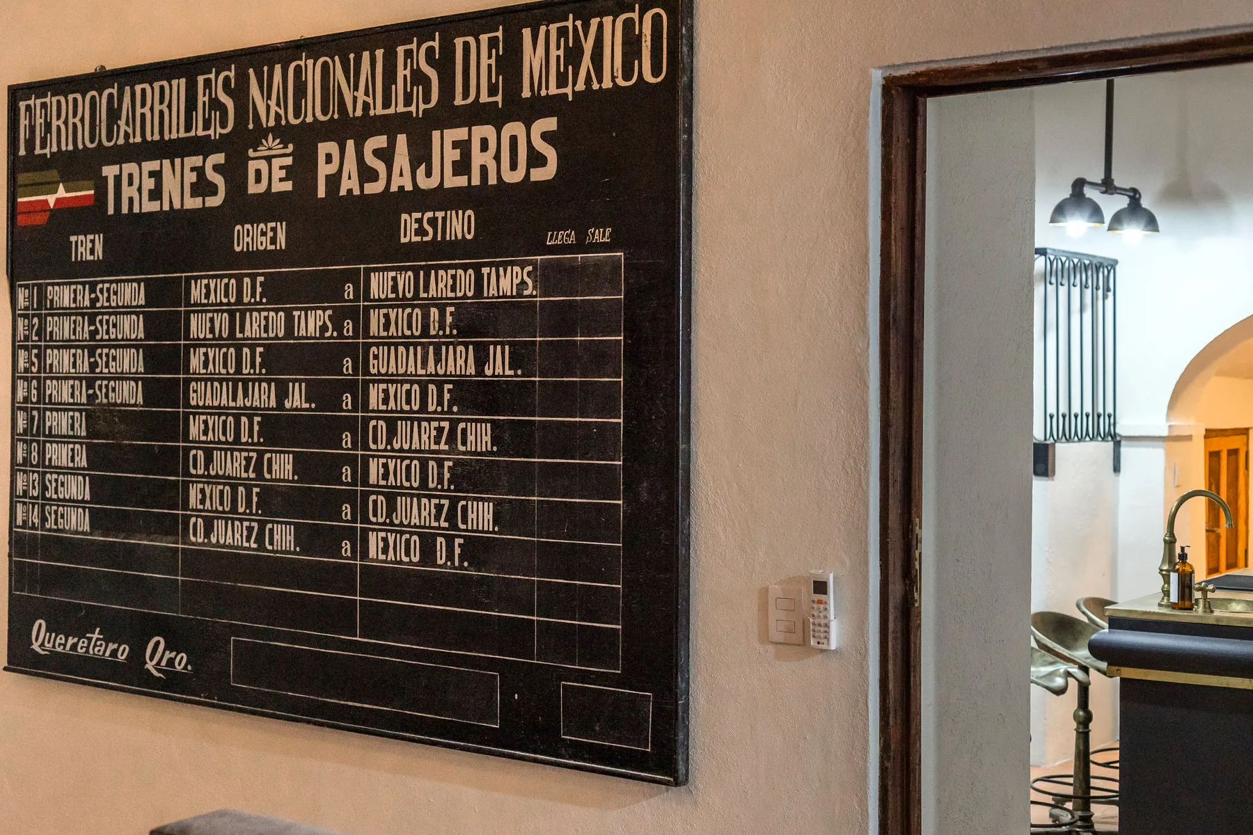 A wall-mounted railway timetable hangs beside a doorway opening onto a tiled room.