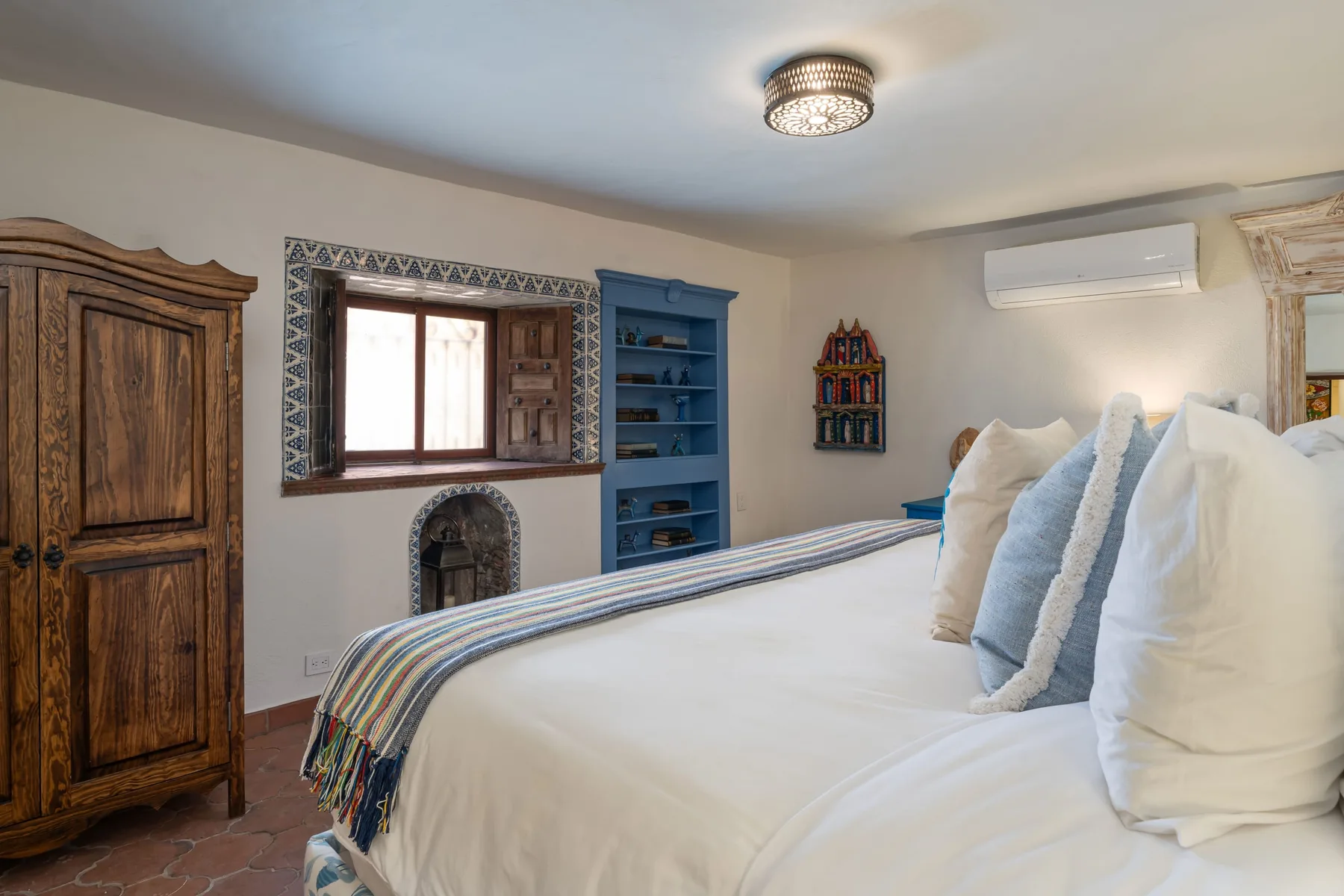 A bedroom with a large bed, a wooden wardrobe, and a window.