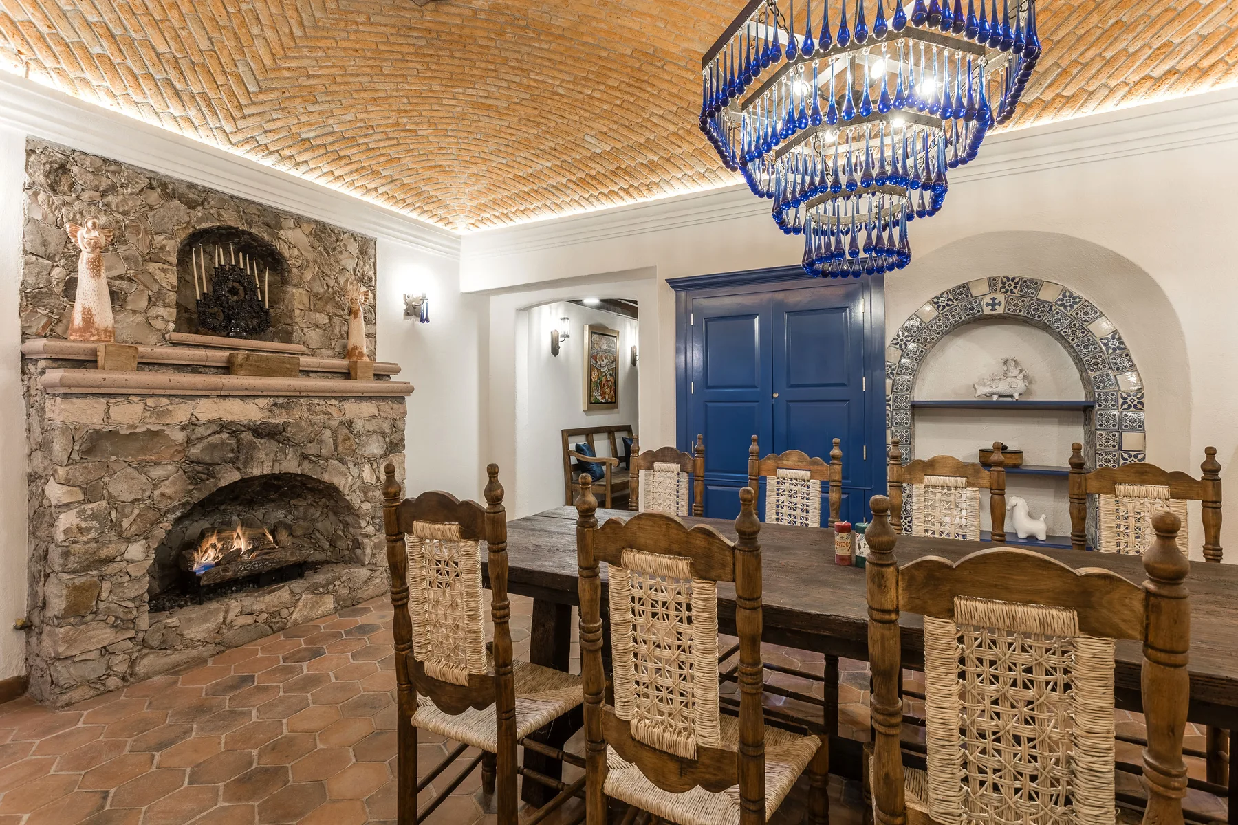 A dining room with a long wooden table beneath a blue chandelier.