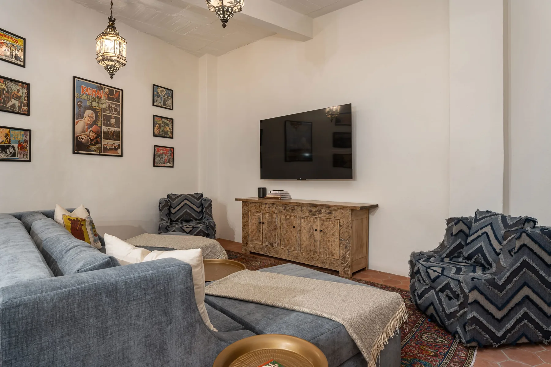 A living room with seating, a wall-mounted television, and framed artwork.