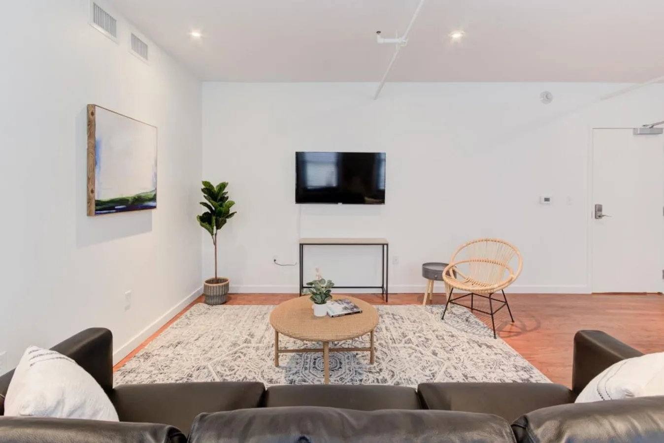 A bright living room with a television, seating, and a patterned rug.