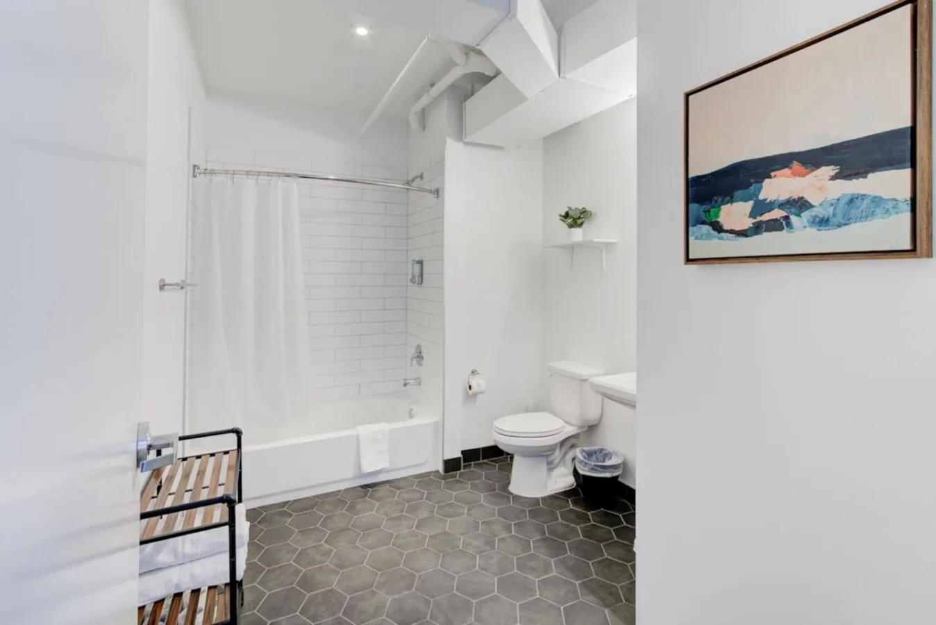 A bright bathroom with a bathtub, shower curtain, and toilet.
