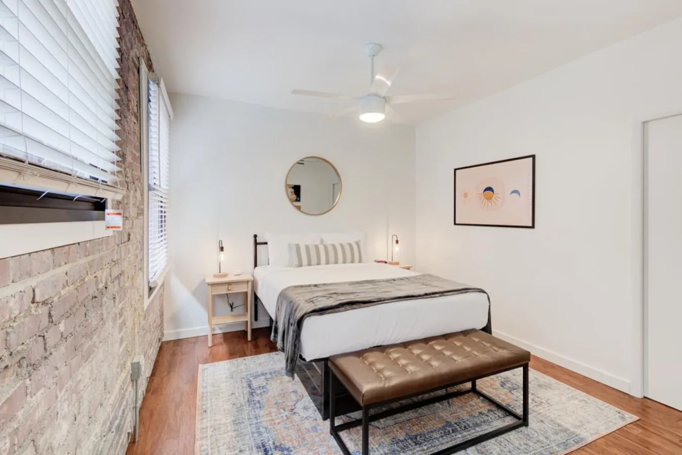 A bedroom with a bed, a bench, and a ceiling fan.