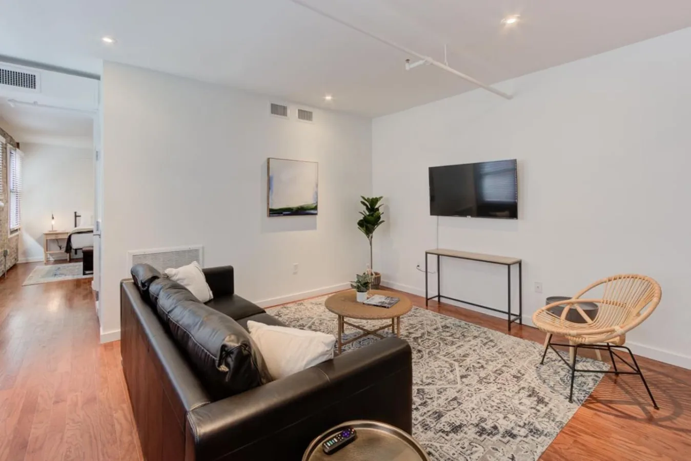 A bright living room with seating, a coffee table, and a wall-mounted television.