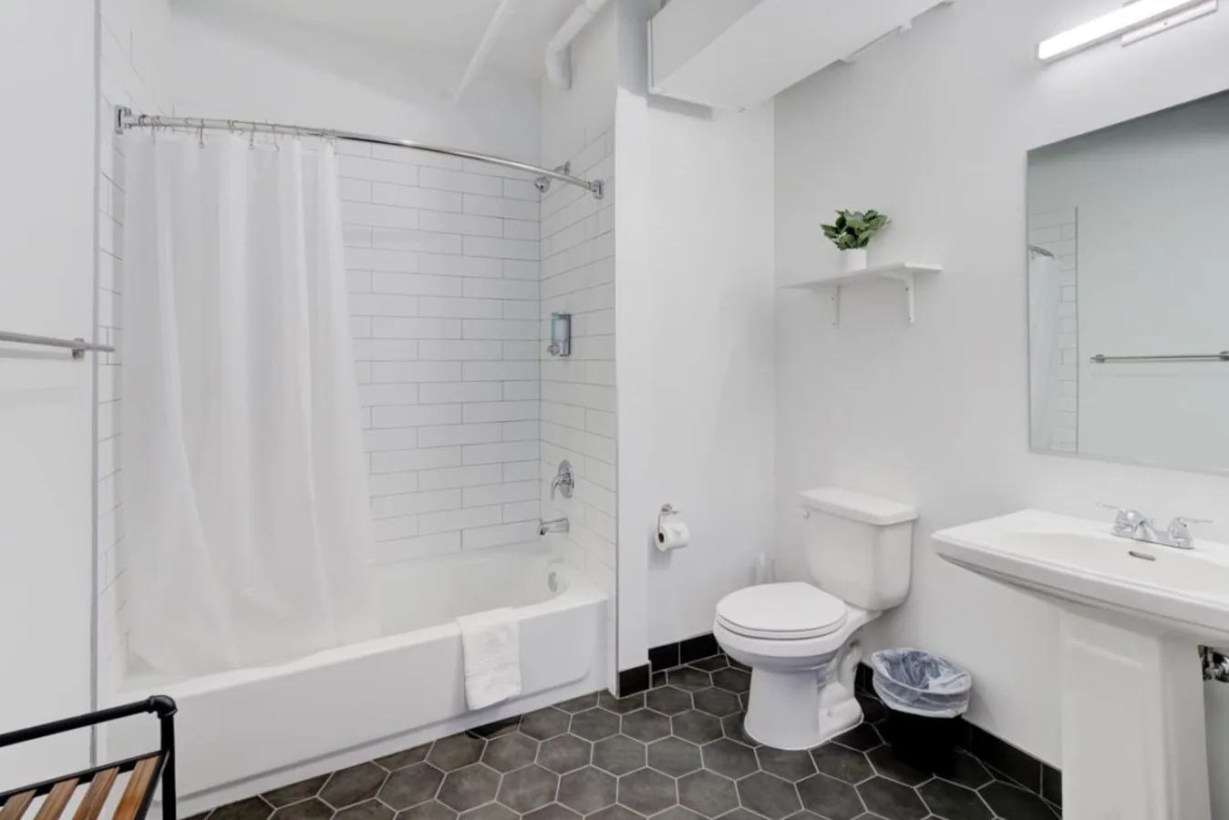 A bright bathroom with a bathtub, shower curtain, toilet, and sink.