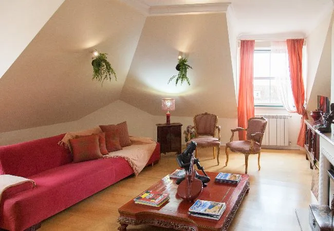 A cozy living room with seating around a coffee table beneath a sloped ceiling.