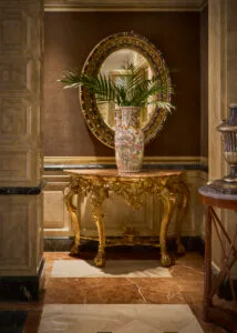 Representative hotel space: An ornate console table with a vase and flowers stands against a decorated wall.
