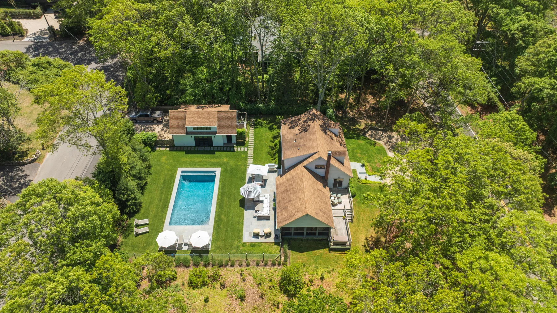 Vista aérea de una casa y una piscina rodeadas de árboles.