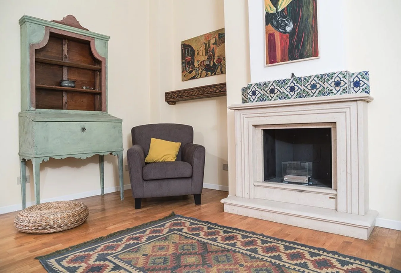 Una sala de estar tiene un sillón junto a una chimenea y una alfombra estampada.