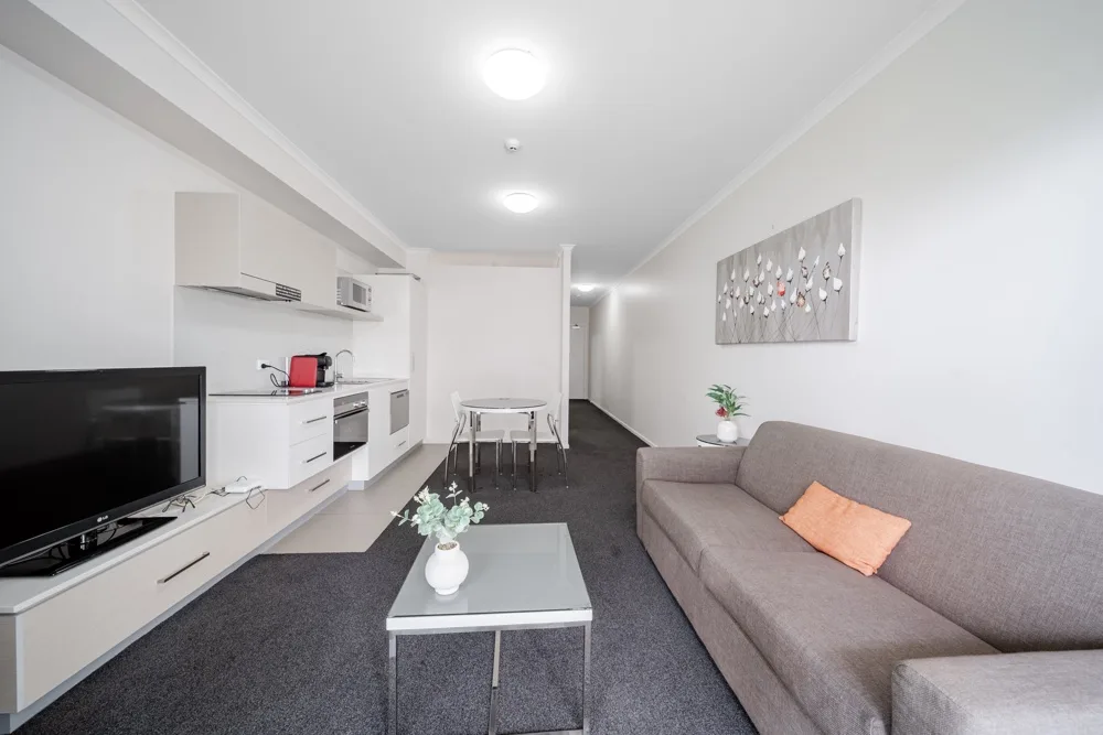 Una sala de estar moderna con sofá, mesa de centro y cocina compacta.