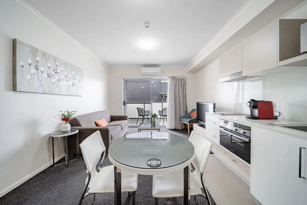 Una luminosa cocina-comedor de planta abierta con una mesa redonda de cristal.