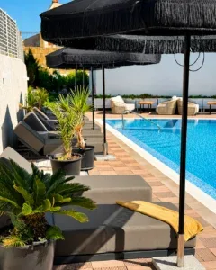 Espacio representativo del hotel: Asientos junto a la piscina, bajo sombrillas grandes.
