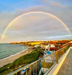 Espacio representativo del hotel: Un complejo junto al mar mira a la playa bajo un arcoíris.