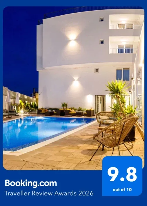 Espacio representativo del hotel: Un edificio hotelero iluminado da a una piscina exterior y una zona de asientos de noche.