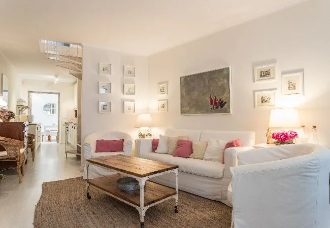 A bright living room with seating arranged around a wooden coffee table.