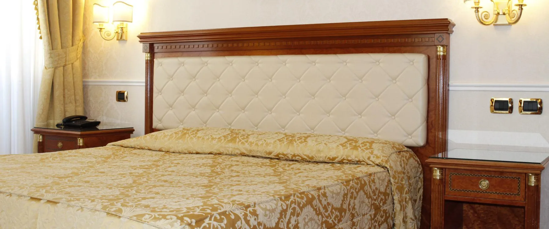Representative hotel space: A bedroom with a large bed, bedside tables, and wall sconces.